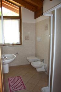 a bathroom with two sinks and a toilet and a window at Casa Costa del Sol in Molveno