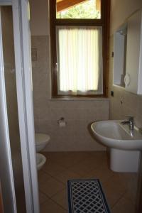 a bathroom with a sink and a toilet and a window at Casa Costa del Sol in Molveno