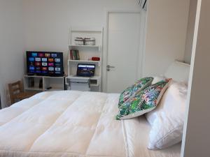 een slaapkamer met een wit bed en een televisie bij Estudio con parrillero y vista al mar in Punta del Este