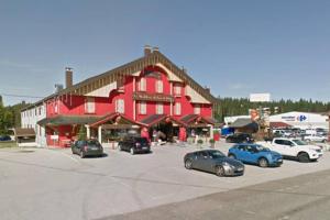 a large red building with cars parked in a parking lot at Magnifique Studio de 20m2 pour 1 à 4 personnes in Les Rousses
