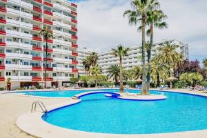 ein Swimmingpool mit Palmen vor einem Gebäude in der Unterkunft Verano ETERNO en Mallorca - Alcudia! in Alcúdia