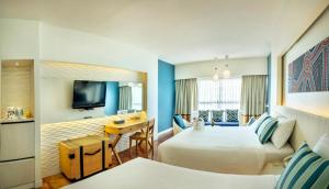 a hotel room with two beds and a desk at Jomtien Palm Beach Hotel and Resort - SHA Extra Plus in Jomtien Beach