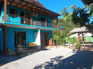 a blue house with a balcony and a driveway at Morada das Orquídeas in Guarda do Embaú