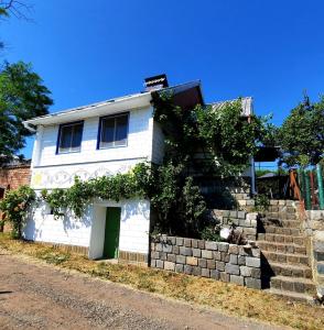 a white house with a green door and a wall at Malovaný sklípek in Hlohovec