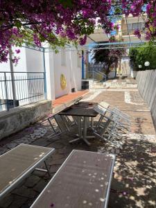 a picnic table and chairs under a tree with purple flowers at Case Vacanze Ganimede in Sperlonga