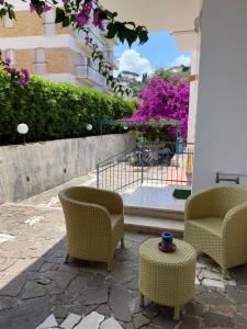 d'une terrasse avec 2 chaises et une table ornée de fleurs violettes. dans l'établissement Case Vacanze Ganimede, à Sperlonga