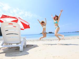 two girls jumping on the beach next to a beach chair at Pension Sea Friend in Tokashiki