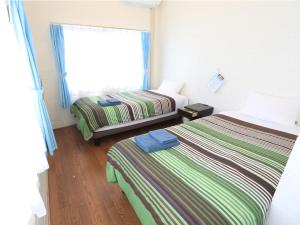 a hotel room with two beds and a window at Pension Sea Friend in Tokashiki