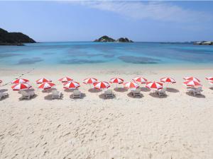 a group of red and white umbrellas on a beach at Pension Sea Friend in Tokashiki