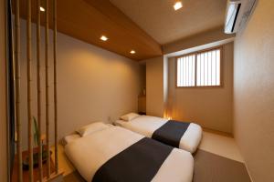 two beds in a small room with a window at Shirakabanoyado - EBISU in Osaka