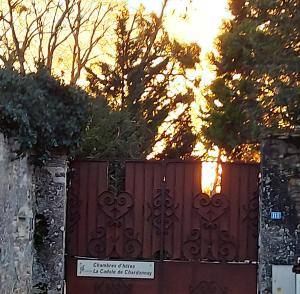 una cerca con una puerta con la puesta de sol en el fondo en La Cadole de Chardonnay, en Chardonnay