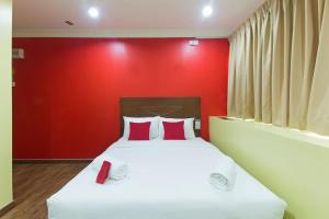 Un dormitorio con una pared roja y una cama con almohadas rojas. en Hotel Sunjoy9 Bandar Sunway en Petaling Jaya