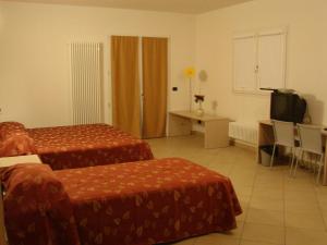 ボローニャにあるBassini Residenceのベッド2台、デスク、テレビが備わるホテルルームです。