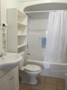 a white bathroom with a toilet and a sink at Seawinds Motel & Cottages in Digby