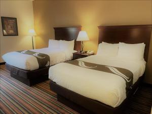 una camera d'albergo con due letti con lenzuola bianche di Quality Inn Danville - University Area a Danville