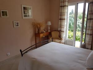 a bedroom with a large white bed with a window at La Montignonne in Montigny-sur-Loing