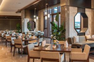 un ristorante con tavoli e sedie in legno e finestre di HUALUXE Suzhou Bay Hot Spring Resort a Suzhou