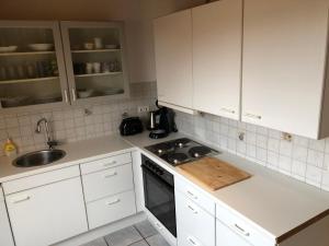 a kitchen with white cabinets and a stove and a sink at Monteur - Privat Zimmer Langerwehe Geich in Langerwehe
