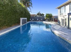 a swimming pool with blue water in front of a house at Shellharbour Seaside Escape in Shellharbour