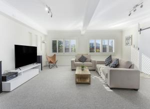 a living room with couches and a flat screen tv at Shellharbour Seaside Escape in Shellharbour