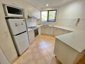 uma cozinha com um frigorífico branco e um lavatório em Beaches Holiday Resort em Port Macquarie