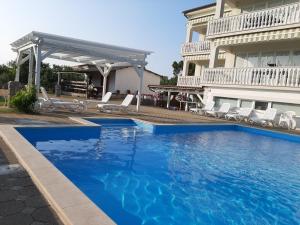 a large blue swimming pool next to a house at Apartments Gorančica in Malinska