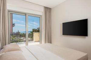 a white bedroom with a bed and a large window at Plaza Apartments in Opatija