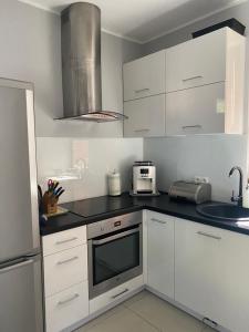 a kitchen with white cabinets and a microwave at Hire House in Pobierowo