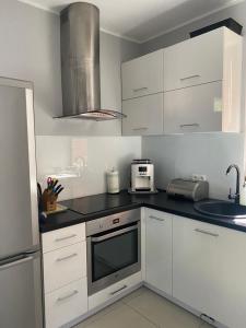 kuchnia z białymi szafkami i mikrofalówką w obiekcie Hire House w Pobierowie