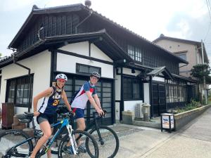 two people on bikes in front of a building at B&B MIKAWA 5 - Villas with BBQ Terrace in Kanazawa