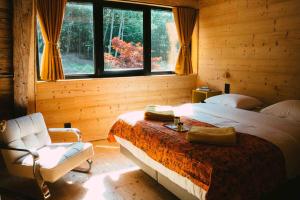 ein Schlafzimmer mit einem Bett und einem Stuhl und einem Fenster in der Unterkunft Le Grand Petit Prince - Domaine de Charme - Jacuzzis privatifs in Guebwiller