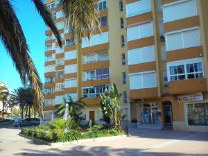 wysoki żółty budynek z palmami przed nim w obiekcie Estudio sol y playa w mieście Algarrobo-Costa