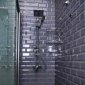 a shower in a bathroom with a brick wall at Central Hostel in Sheki