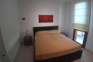 ein Schlafzimmer mit einem Bett mit einer roten Rose an der Wand in der Unterkunft Casetta Emma, trilocale Elmas, areoporto elegante silenzioso in Elmas