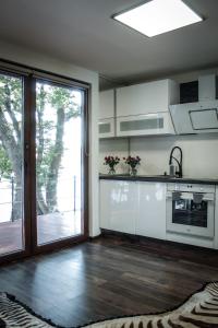 a kitchen with white cabinets and a sliding glass door at Golden Beach Apartment in Chlʼaba