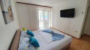 a bedroom with a bed with blue pillows and a television at Apartmani Batinović - Baška Voda in Baška Voda