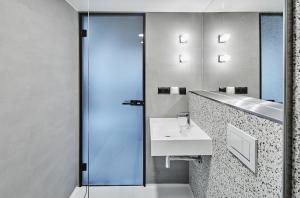 a bathroom with a sink and a glass shower at New Port Aparthotel in Kraków +36 photos