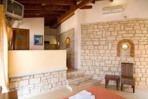 a living room with a stone wall and a tv at Sunset Hotel Parga in Parga