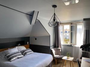 een slaapkamer met een bed, een stoel en een raam bij Hôtel La Réserve de Brive in Brive-la-Gaillarde