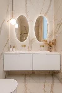 a white bathroom with two mirrors and a sink at Plaza Apartments in Opatija