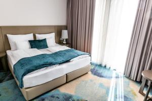 Hotel Seven في فيلاخ: غرفة نوم بسرير كبير مع بطانية زرقاء