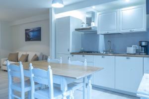 a kitchen with white cabinets and a table and chairs at Martalagattahome in San Felice del Benaco