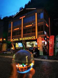 a person holding a wine glass in front of a building at Dunya Residence in Uzungöl