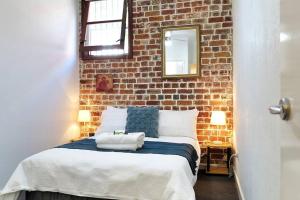 een slaapkamer met een bed met een bakstenen muur bij Underwater Oasis Freo - 2BRM with Courtyard & 1 Car Bay in Fremantle