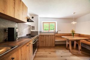 a kitchen with wooden cabinets and a wooden table at Schnitzers Ferienheisl in San Leonardo in Passiria