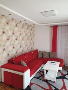 a living room with a red couch and a table at Lux Apartman Ristić 2 in Soko Banja