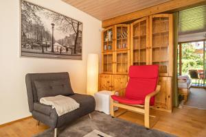 ein Wohnzimmer mit einem roten Stuhl und einem Stuhl in der Unterkunft Haus Sonnenschein Sonnenterrasse in Bermatingen