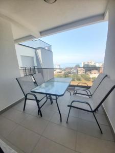 einen Glastisch und zwei Stühle auf dem Balkon in der Unterkunft Apartmani Aida in Dobra Voda