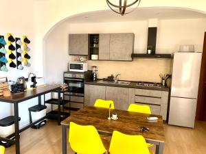 Verba Mundi Guest House في أولبيا: مطبخ بطاولة خشبية وكراسي صفراء