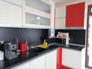a kitchen with red and white cabinets and a sink at White home-apartament in Burgas City